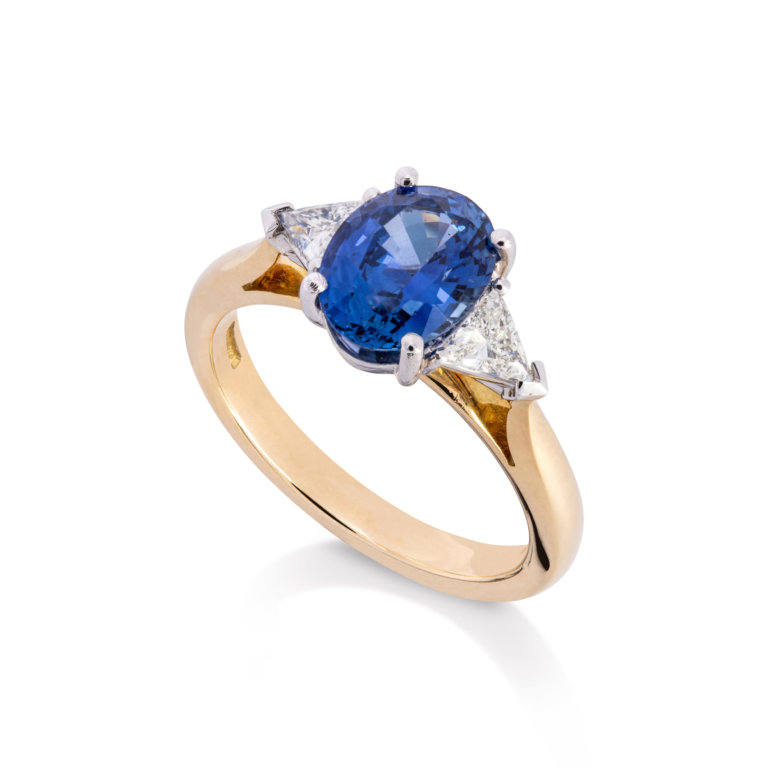 Image of an oval Sapphire and Trilliant Cut Diamond Three Stone Ring in yellow gold and platinum