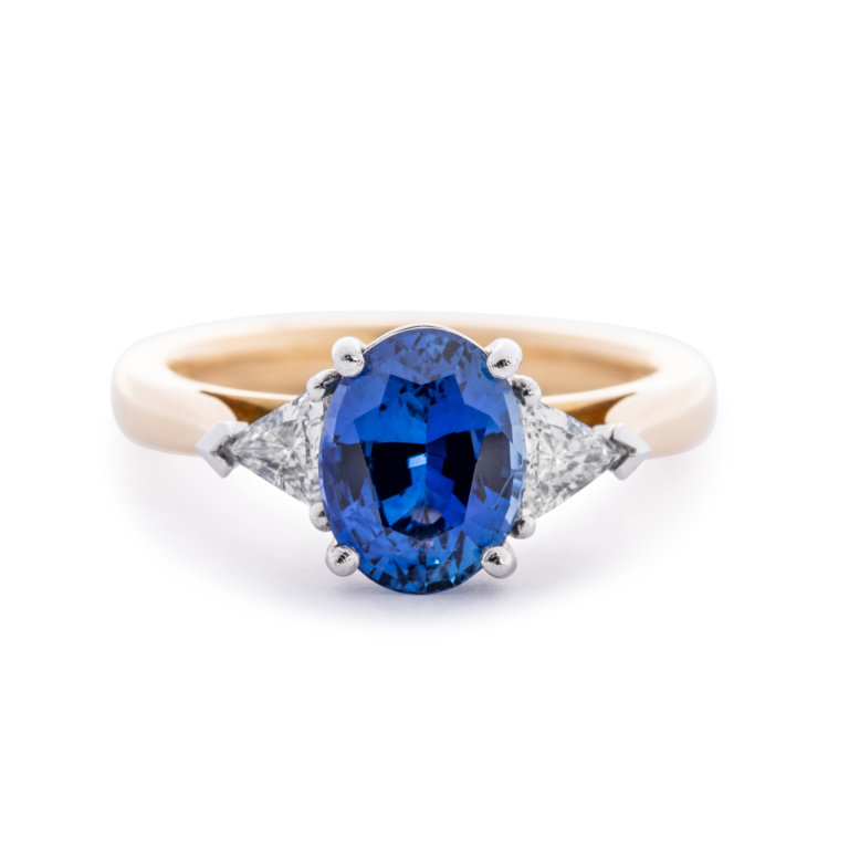 Image of an Oval Sapphire and Trilliant Cut Diamond Three Stone Ring in yellow gold and platinum