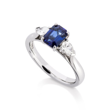 Image of an Emerald Cut Sapphire and Pear Cut Diamond Three Stone Ring in platinum