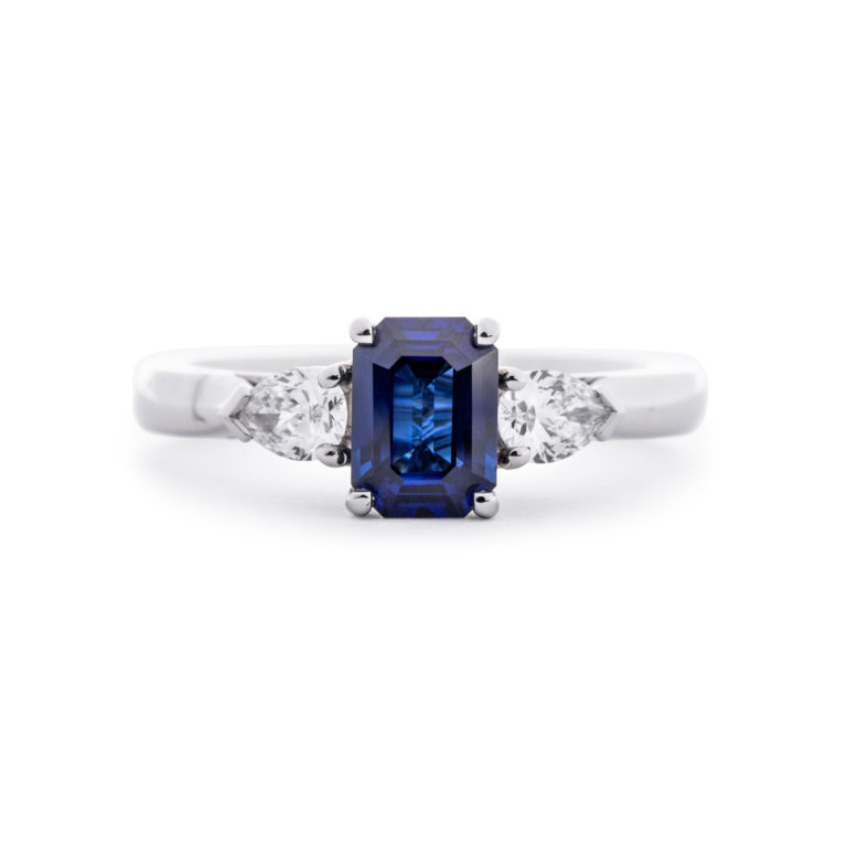 Image of an Emerald Cut Sapphire and Pear Cut Diamond Three Stone Ring in platinum