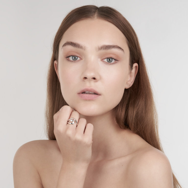 Image of a lady holding her hand under her chin to display a silver hook ring by designer Shaun Leane
